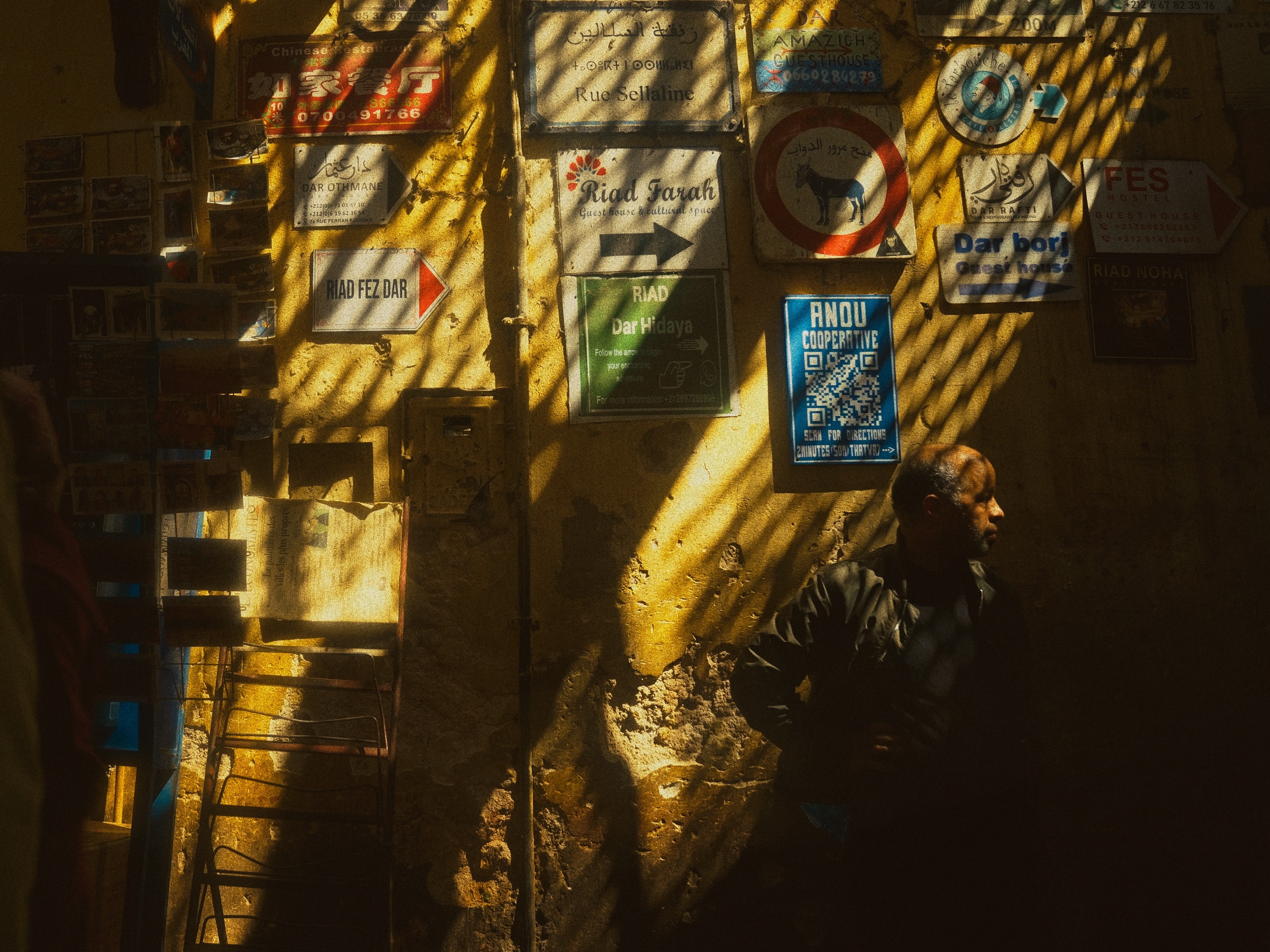 Sunlight cuts through the medina, signs pointing every direction.