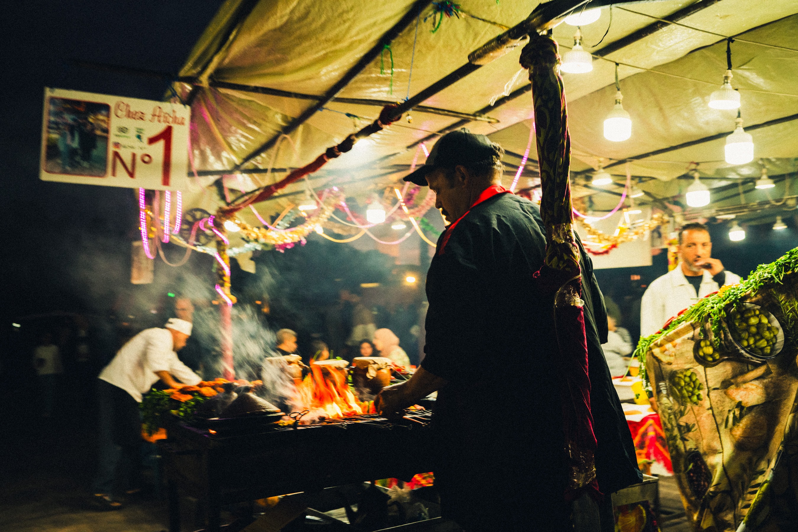 Smoke and firelight over the night market grill.